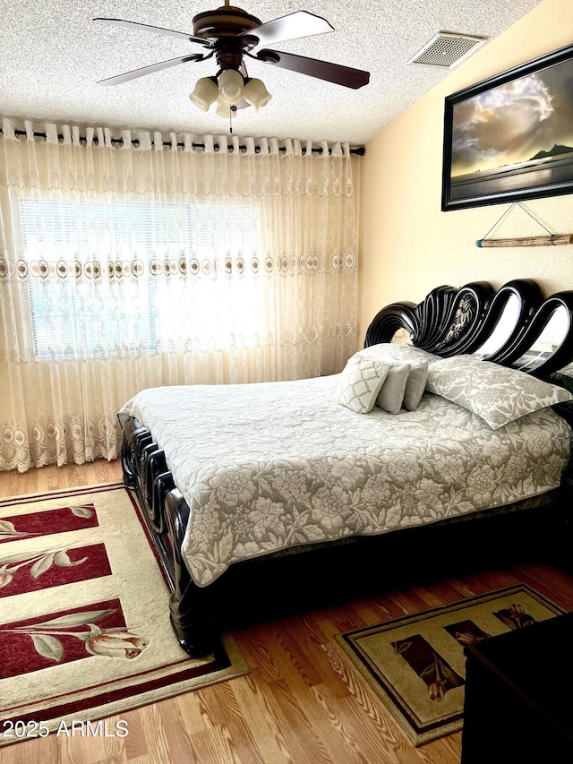 bedroom with ceiling fan, a textured ceiling, and hardwood / wood-style flooring