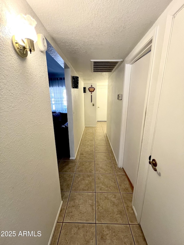 hall with tile patterned flooring and a textured ceiling