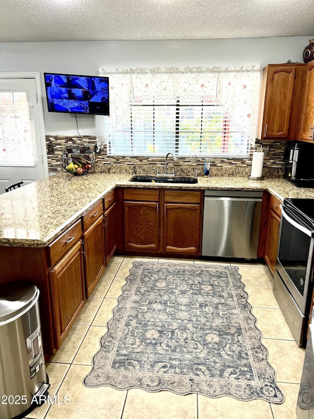 kitchen with light stone countertops, a textured ceiling, appliances with stainless steel finishes, sink, and light tile patterned flooring