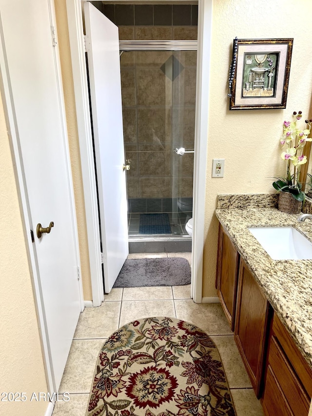 bathroom with toilet, a shower with door, tile patterned floors, and vanity