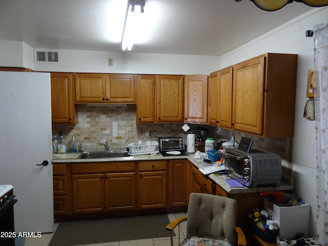 kitchen featuring brown cabinetry, light countertops, visible vents, and a sink