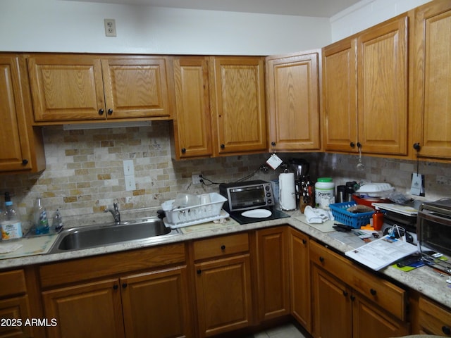 kitchen with backsplash, a sink, and brown cabinets