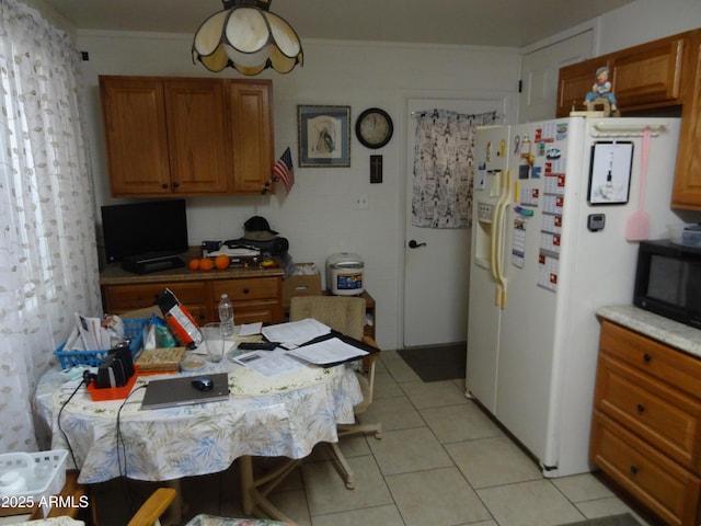 kitchen with black microwave, light tile patterned floors, ornamental molding, white fridge with ice dispenser, and brown cabinetry