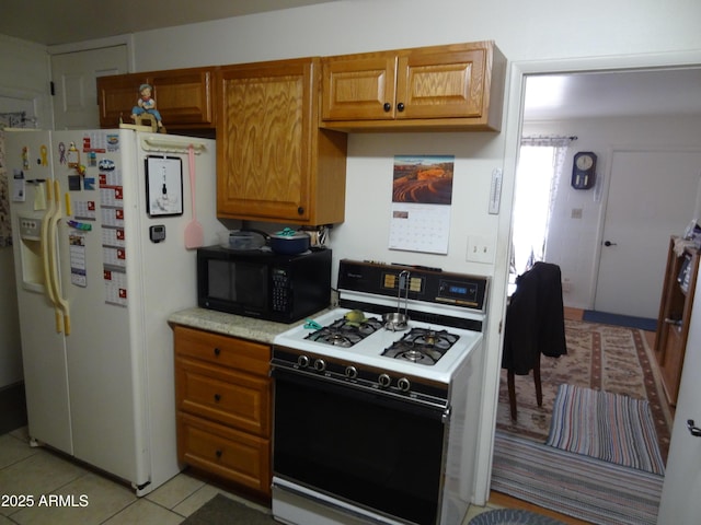 kitchen featuring light tile patterned floors, light countertops, white appliances, and brown cabinets