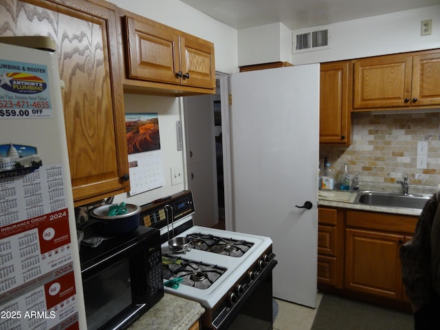 kitchen with black microwave, a sink, visible vents, fridge, and white gas range