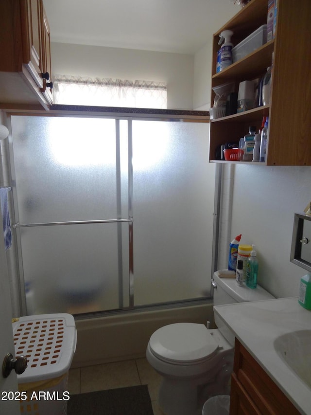 bathroom featuring tile patterned flooring, enclosed tub / shower combo, vanity, and toilet