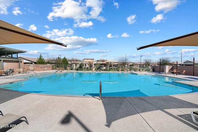 community pool with a patio area and fence