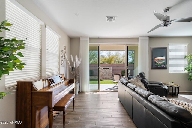 living area with ceiling fan, visible vents, and wood finished floors