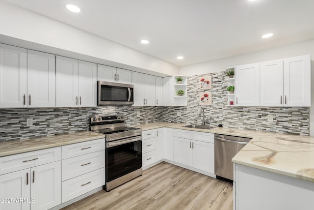 kitchen featuring white cabinets, light wood-style flooring, appliances with stainless steel finishes, open shelves, and a sink