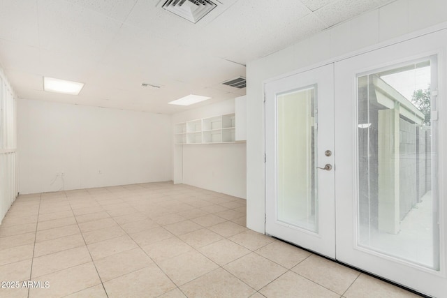 spare room featuring light tile patterned floors, french doors, and visible vents