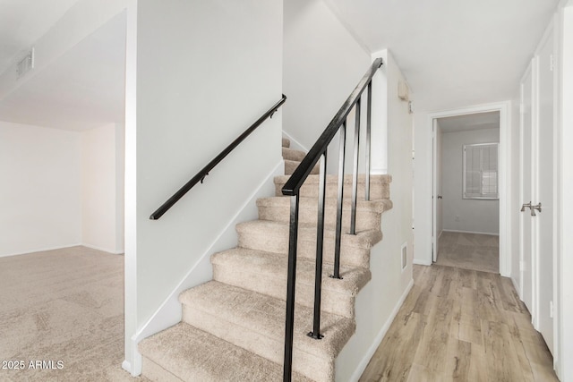 stairs with visible vents, baseboards, and wood finished floors