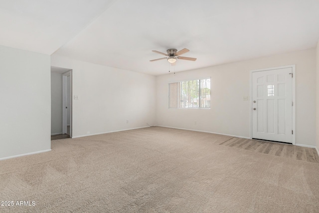 unfurnished living room with a ceiling fan, light carpet, and baseboards