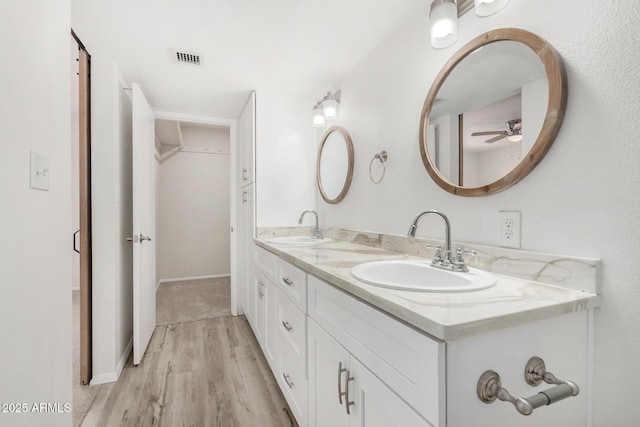 bathroom featuring double vanity, visible vents, a sink, and wood finished floors