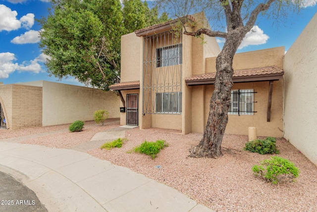 view of front of property with a tile roof, a gate, fence, and stucco siding