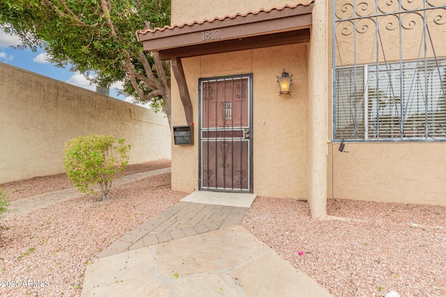 doorway to property with fence and stucco siding