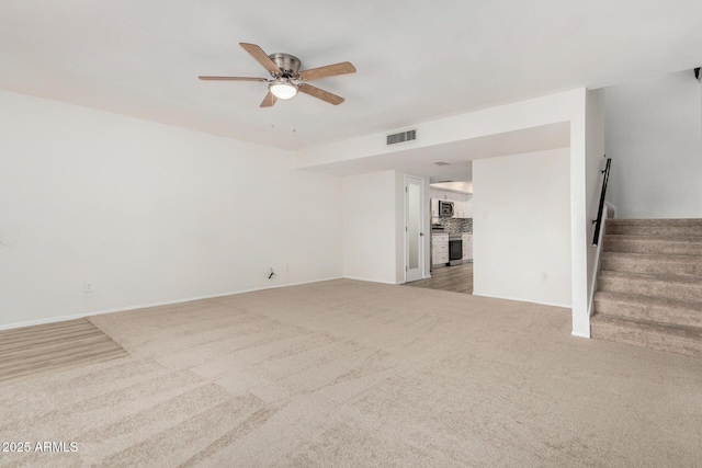 unfurnished living room with light colored carpet, visible vents, stairway, ceiling fan, and baseboards