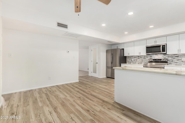 kitchen with stainless steel appliances, tasteful backsplash, light countertops, visible vents, and light wood-style floors