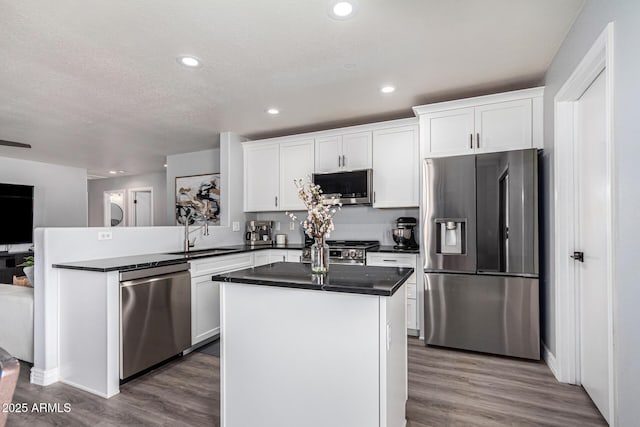 kitchen with stainless steel appliances, white cabinetry, a kitchen island, and sink