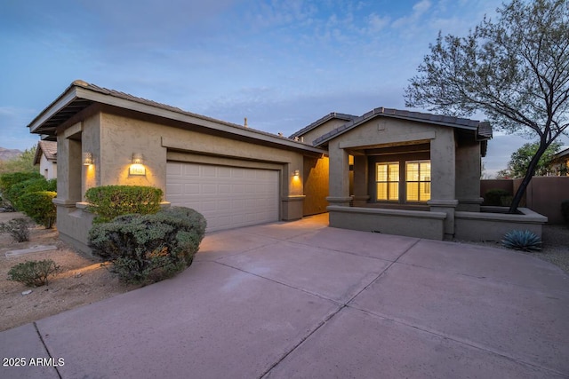 view of front of property featuring a garage, concrete driveway, and stucco siding