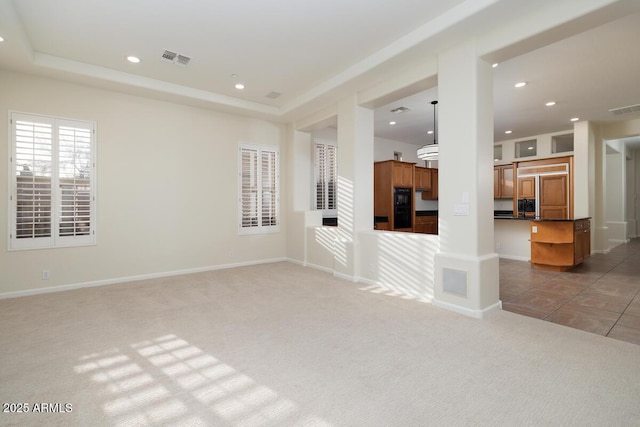 unfurnished living room with recessed lighting, visible vents, light colored carpet, and a raised ceiling