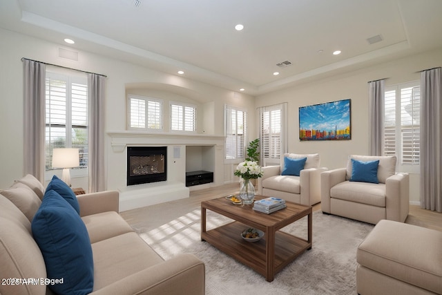 living room with recessed lighting, visible vents, plenty of natural light, and a tray ceiling