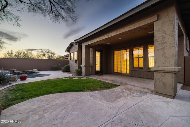 rear view of property with a fenced in pool, fence, stucco siding, a lawn, and a patio