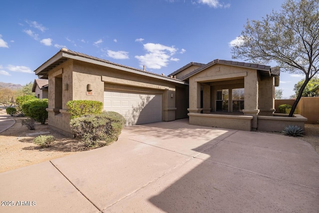 view of front of property with stucco siding, driveway, an attached garage, and a tile roof