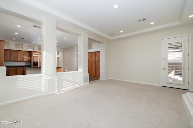 unfurnished living room featuring light carpet, visible vents, recessed lighting, and a tray ceiling