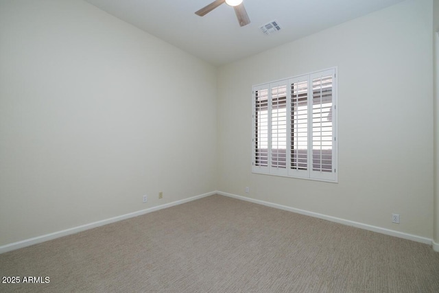 empty room with visible vents, carpet flooring, baseboards, and a ceiling fan