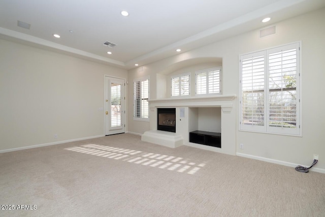 unfurnished living room with recessed lighting, visible vents, carpet floors, and a glass covered fireplace