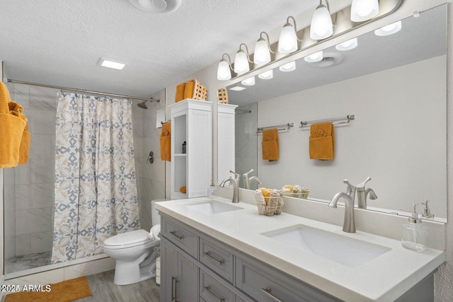 bathroom featuring wood-type flooring, vanity, walk in shower, toilet, and a textured ceiling