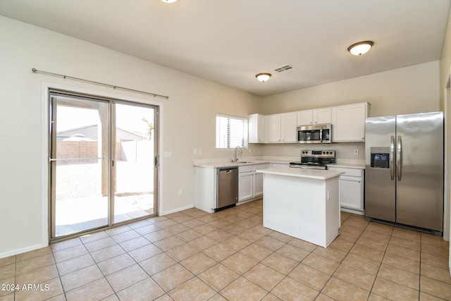 kitchen featuring sink, appliances with stainless steel finishes, white cabinetry, and a center island