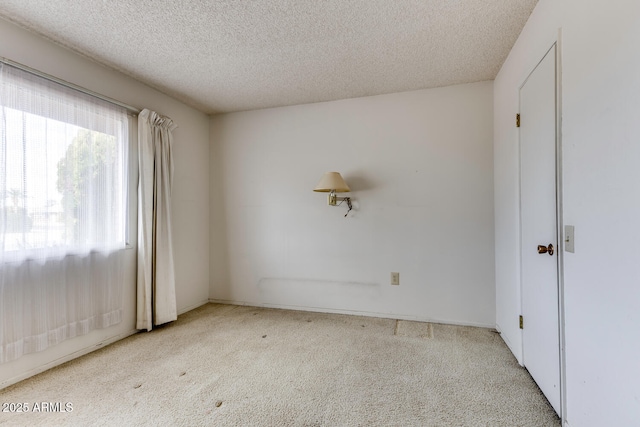 spare room featuring light carpet and a textured ceiling