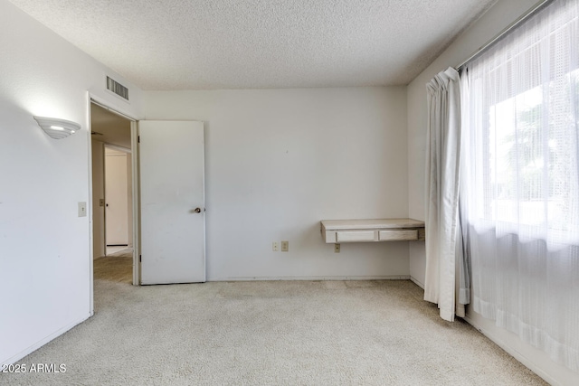 carpeted empty room with a textured ceiling