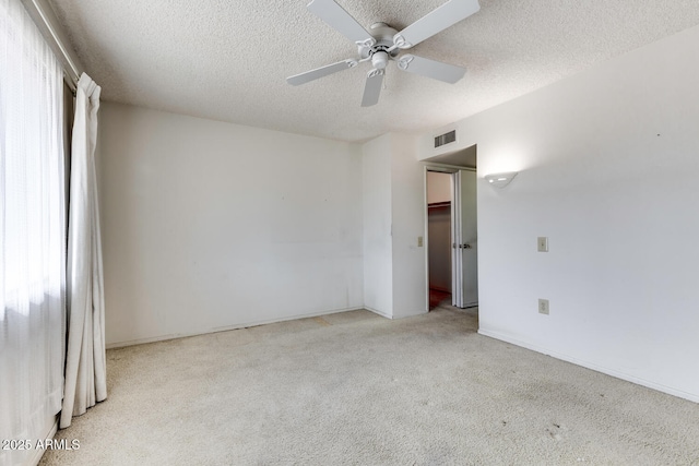 spare room with ceiling fan, light colored carpet, and a textured ceiling