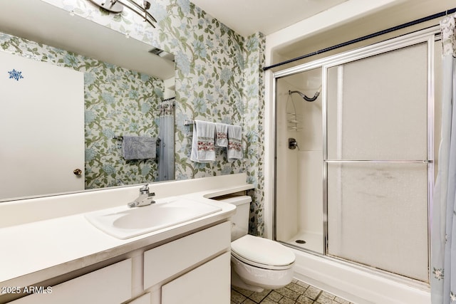 bathroom featuring vanity, a shower with shower door, and toilet