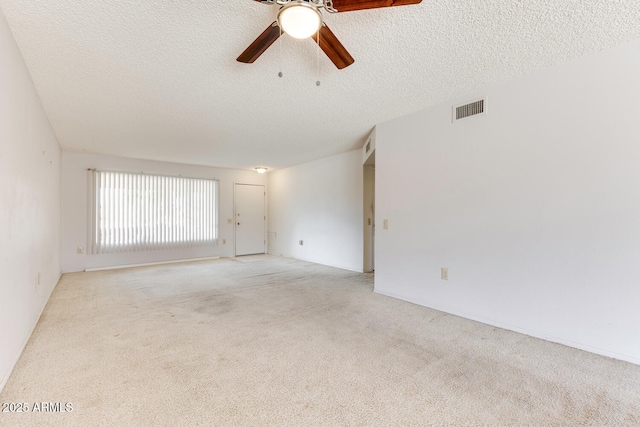 empty room featuring ceiling fan, light carpet, and a textured ceiling