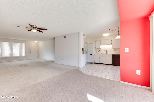 unfurnished living room with ceiling fan, light colored carpet, sink, and a textured ceiling