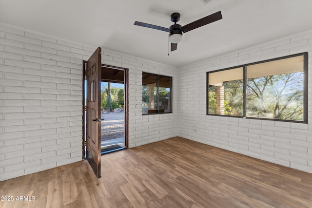 27610 W Gill Rd, Morristown, AZ 85342 - spare room featuring brick wall, wood finished floors, and a ceiling fan