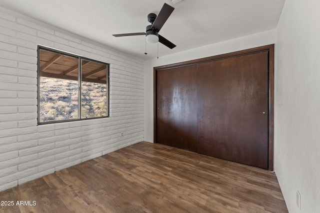 27610 W Gill Rd, Morristown, AZ 85342 - unfurnished bedroom featuring brick wall, wood finished floors, a closet, and ceiling fan
