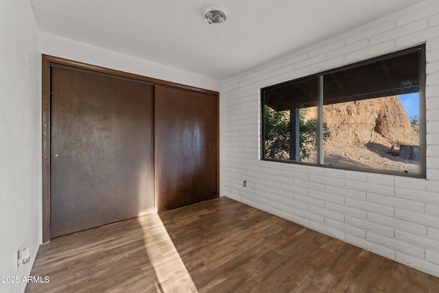 27610 W Gill Rd, Morristown, AZ 85342 - unfurnished bedroom featuring brick wall, wood finished floors, and a closet