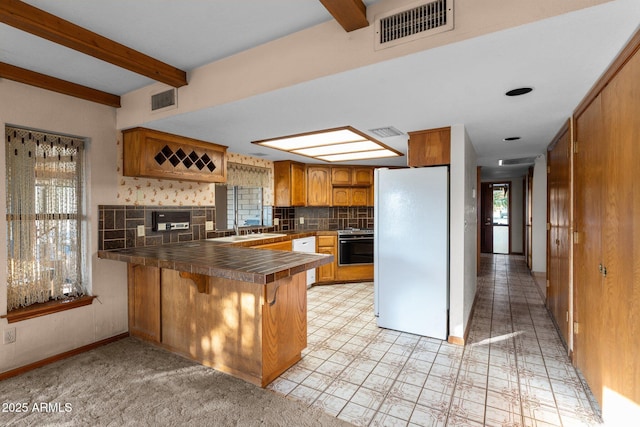 27610 W Gill Rd, Morristown, AZ 85342 - kitchen with freestanding refrigerator, a peninsula, decorative backsplash, brown cabinetry, and beam ceiling