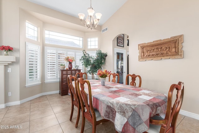 tiled dining space featuring a chandelier and high vaulted ceiling