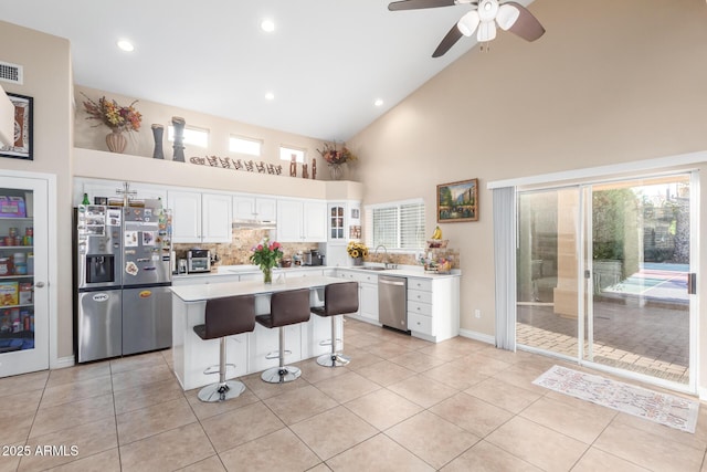 kitchen with sink, light tile patterned floors, appliances with stainless steel finishes, white cabinets, and a kitchen island