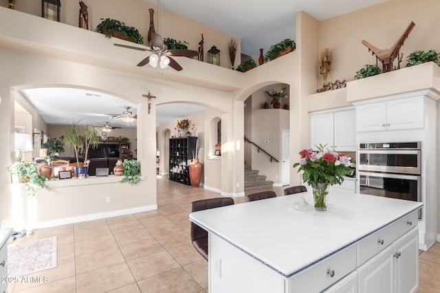 kitchen with double oven, light tile patterned floors, white cabinets, and a high ceiling