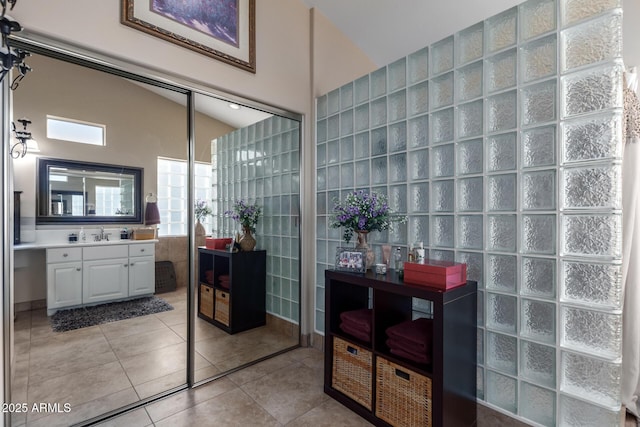 bathroom featuring lofted ceiling, tile patterned floors, vanity, and tile walls