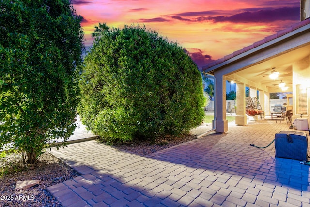 patio terrace at dusk featuring ceiling fan