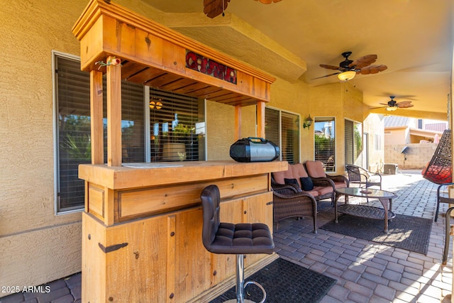 view of patio with ceiling fan and a bar