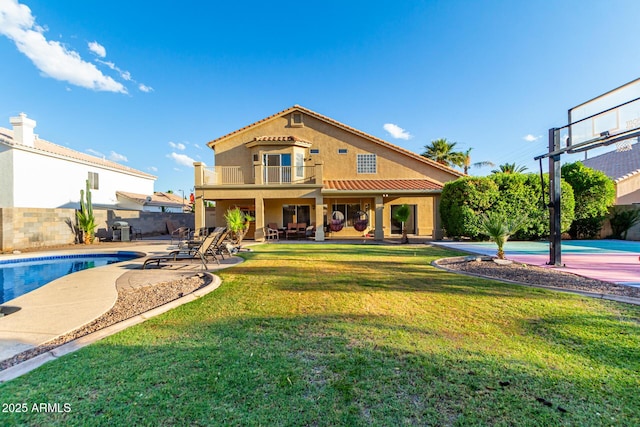 rear view of house with a fenced in pool, a patio, a balcony, and a lawn