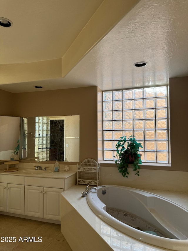 bathroom featuring tiled bath, tile patterned flooring, and vanity